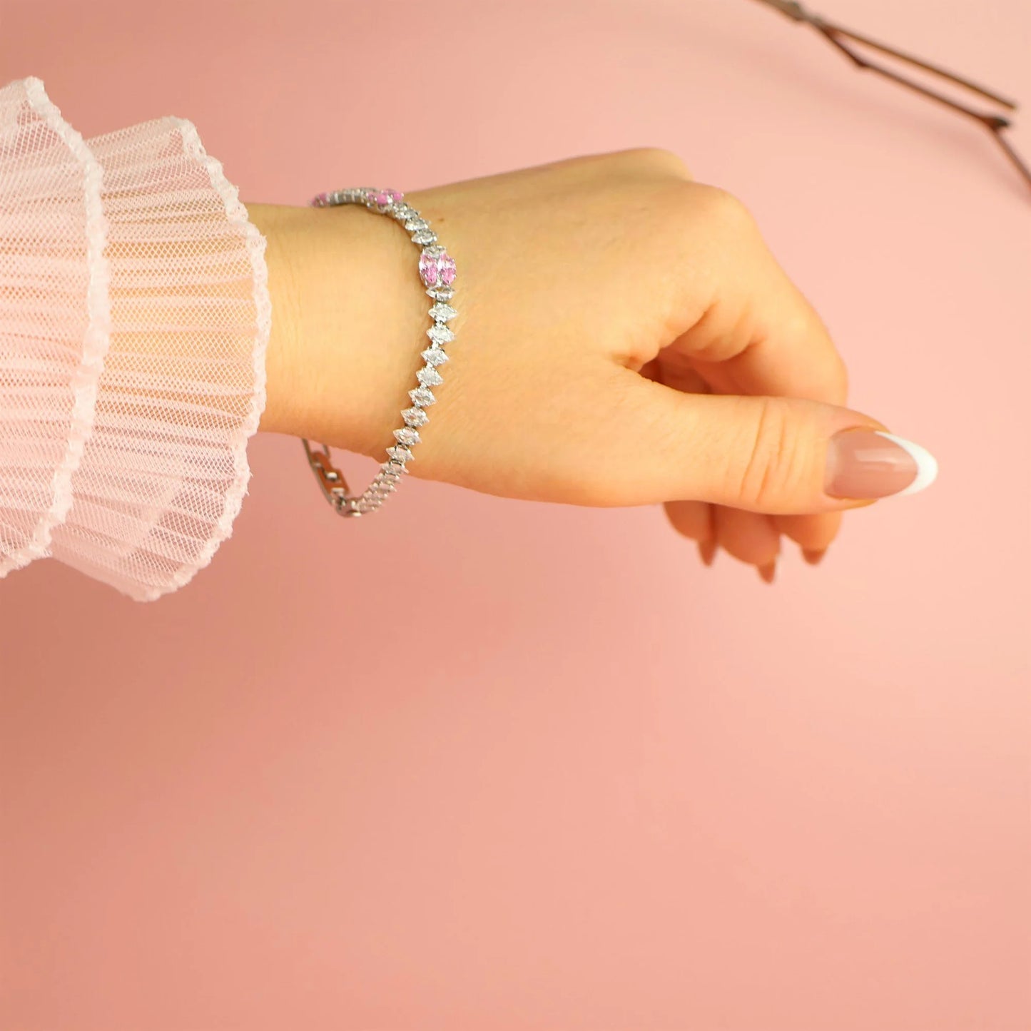 Woman wearing silver bracelet with pink zircon stones on wrist